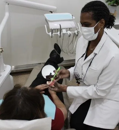 Cheryl demonstrating toothbrushing with a dental model and toothbrush
